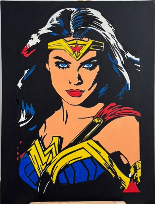 Portrait peint de Wonder Woman au diadème étoilé, bustier bleu et emblème doré, sur fond noir, posé sur un chevalet en bois.