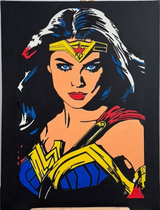 Portrait peint de Wonder Woman au diadème étoilé, bustier bleu et emblème doré, sur fond noir, posé sur un chevalet en bois.